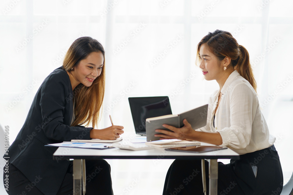 Two beautiful Asian businesswoman discussing financial paperwork and company account. Two beautiful Asian businesswoman discussing financial paperwork and company account.