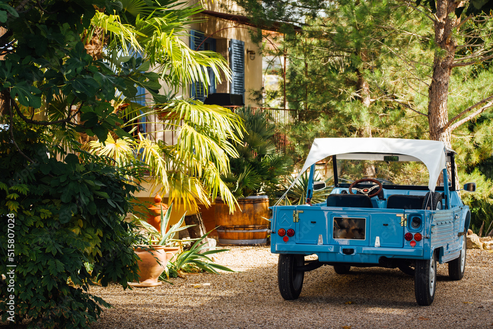 une voiture garée sous un palmier dans un joli jardin. Une jolie Citroën méhari bleue stationnée devant une maison. une voiture garée sous un palmier dans un joli jardin. Une jolie Citroën méhari bleue stationnée devant une maison.