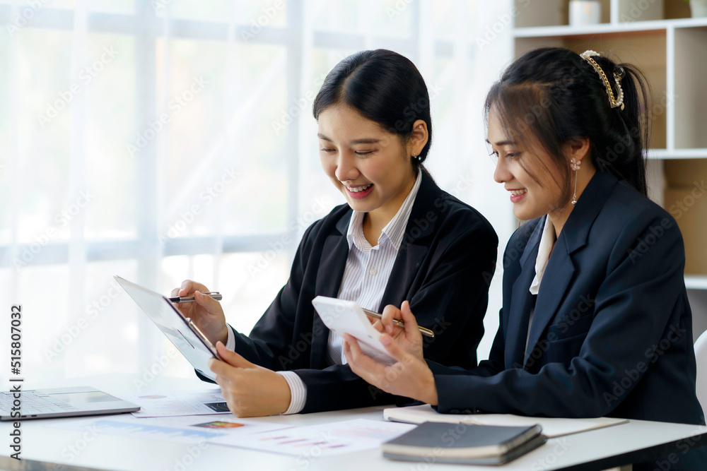 Two beautiful Asian businesswoman discussing financial paperwork and company account. Two beautiful Asian businesswoman discussing financial paperwork and company account.