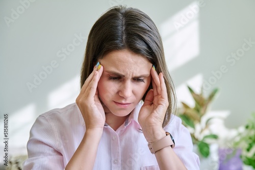 Young stressed woman with headache holding her head with her hands