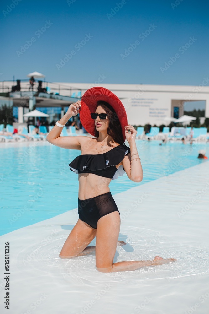 beautiful girl in a hat relaxing by the pool, girl in the pool, summer vacation