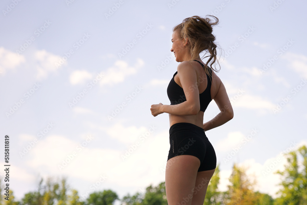 happy fit fitness athletic girl runner running, jogging, young beautiful woman is smiling training outdoors at summer sunny day in the morning in black top and shorts happy fit fitness athletic girl runner running, jogging, young beautiful woman is smiling training outdoors at summer sunny day in the morning in black top and shorts