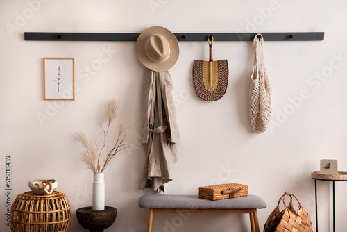 The stylish composition of cosy entryway with wooden basket, carpet, hanger and personal accessories. Beige wall. Home decor. Template. © FollowTheFlow
