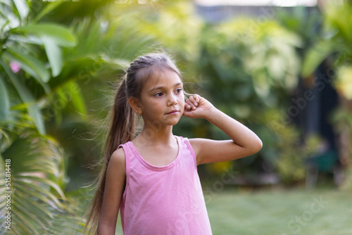 young aboriginal child with long hair in ponytail in garden photo