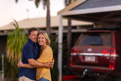 Happy couple embracing in front of home and car photo