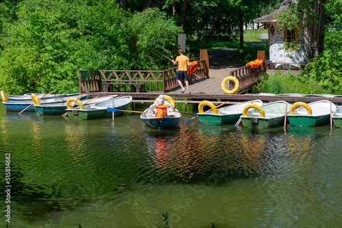 Tourists go for a walk on the water on a boat with oars. There are a lot of available boats for rent on the pier. St. Petersburg, Pavlovsk, 30.06.2022