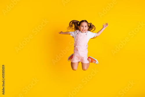 Photo of funky excited preschool lady dressed pink clothes jumping high empty space isolated yellow color background