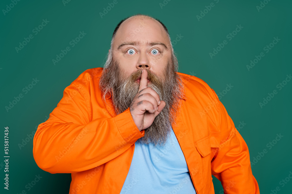 excited bearded man bulging eyes and showing hush sign isolated on green. excited bearded man bulging eyes and showing hush sign isolated on green.