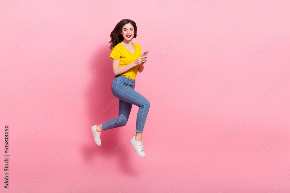 Full body profile portrait of excited active girl running hold telephone isolated on pink color background