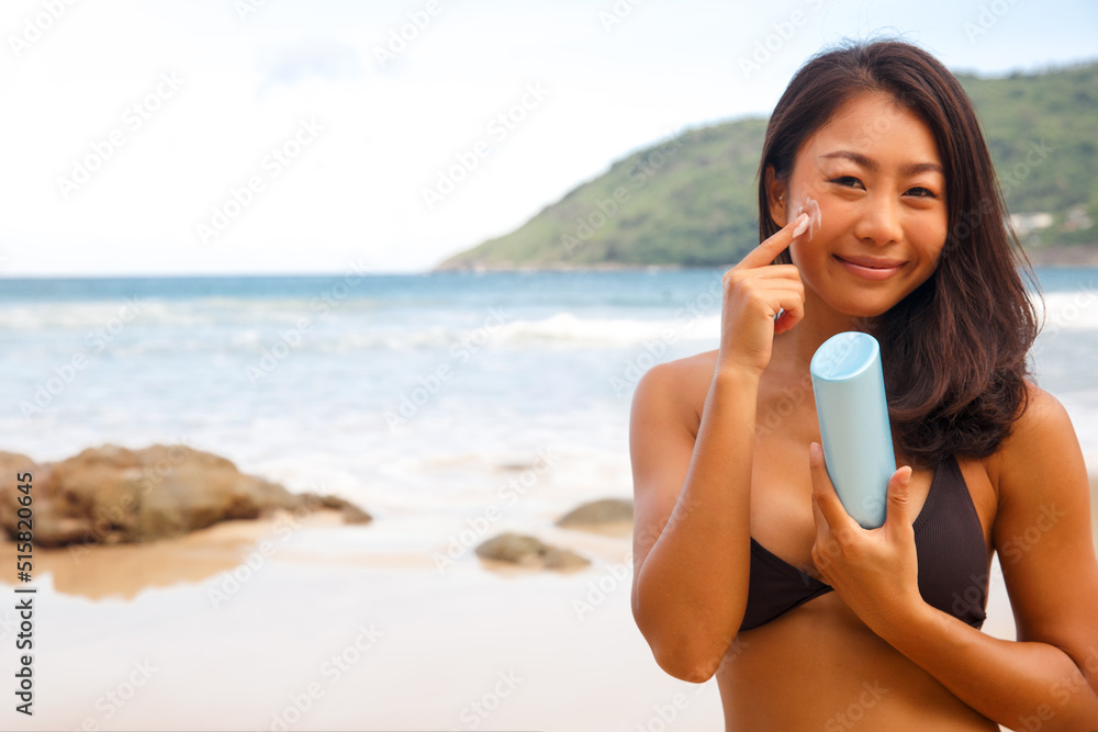 closeup woman applying sunblock cream lotion on beach for broad spectrum UVA, UVB sun protection closeup woman applying sunblock cream lotion on beach for broad spectrum UVA, UVB sun protection