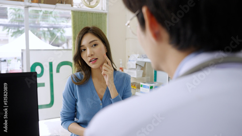 Asian female customer comes to consult about acne and wrinkles on the face with a pharmacist  Thai text in background   Pharmacy