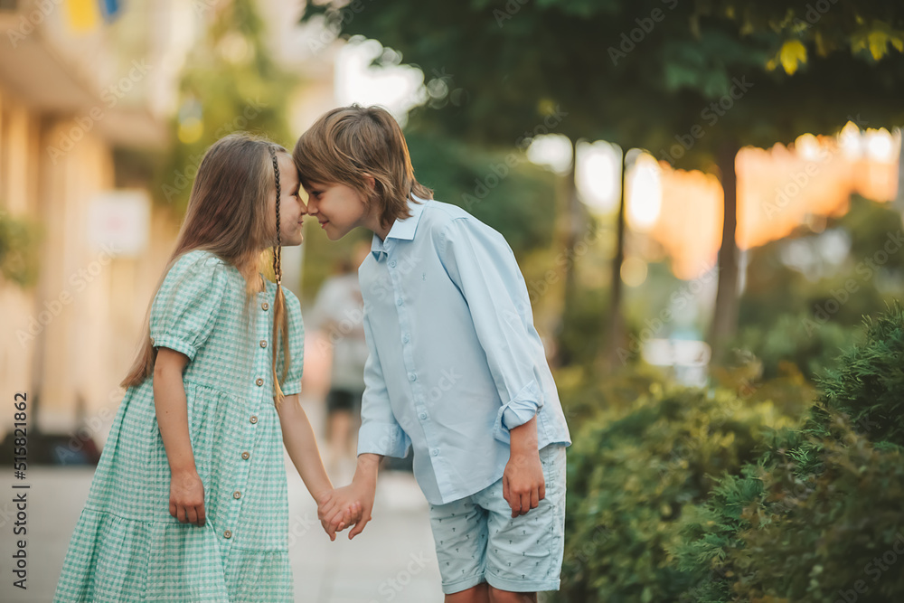 Fototapeta premium A boy and a girl walking together and holding each other hands, look at each other.