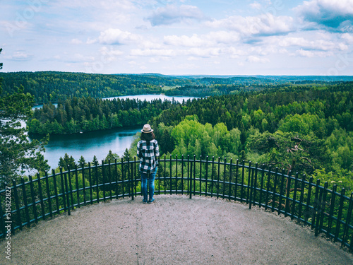 Fotografia A young woman from back on the observation deck among blue lakes and green forests in summer Finland
