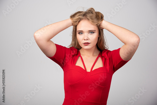 Blonde woman in red outfit holding her hair