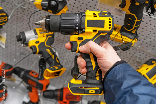 A man in a hardware store chooses a new drill or screwdriver. Screwdriver tool in hand closeup