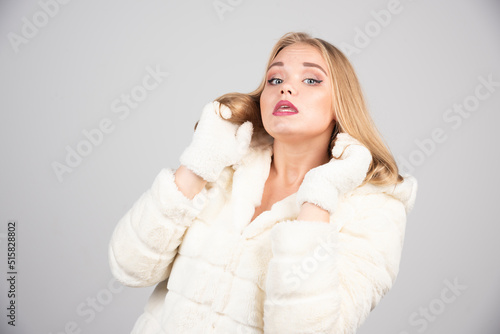 Blonde woman with red lipstick standing on gray background