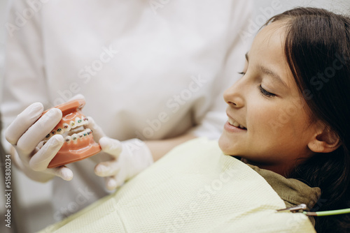 Papier peint Dentist showing braces on false jaw to a child patient