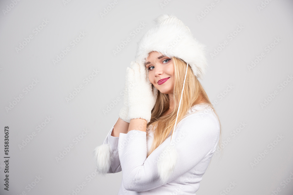 Blonde woman in winter outfit standing on gray background Blonde woman in winter outfit standing on gray background