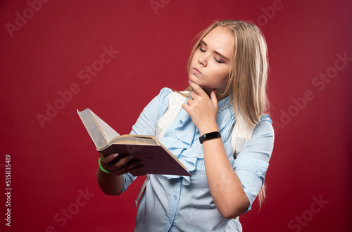 Blonde studentgirl reads a book and thinking carefully photo