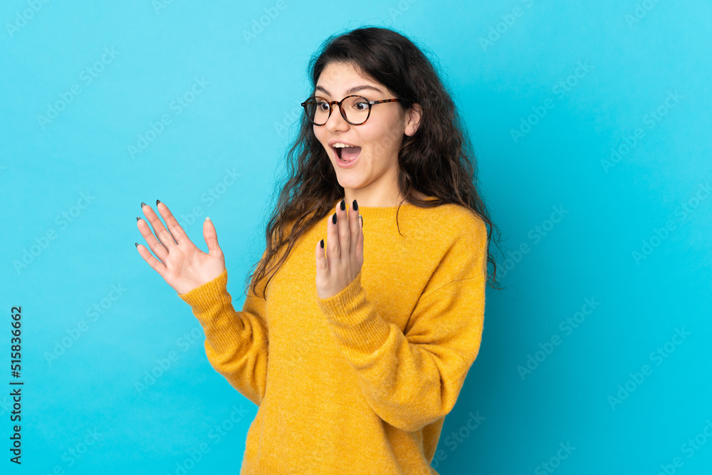 Fototapeta premium Teenager Russian girl isolated on blue background with surprise facial expression