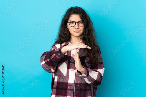 Teenager Russian girl isolated on blue background making time out gesture