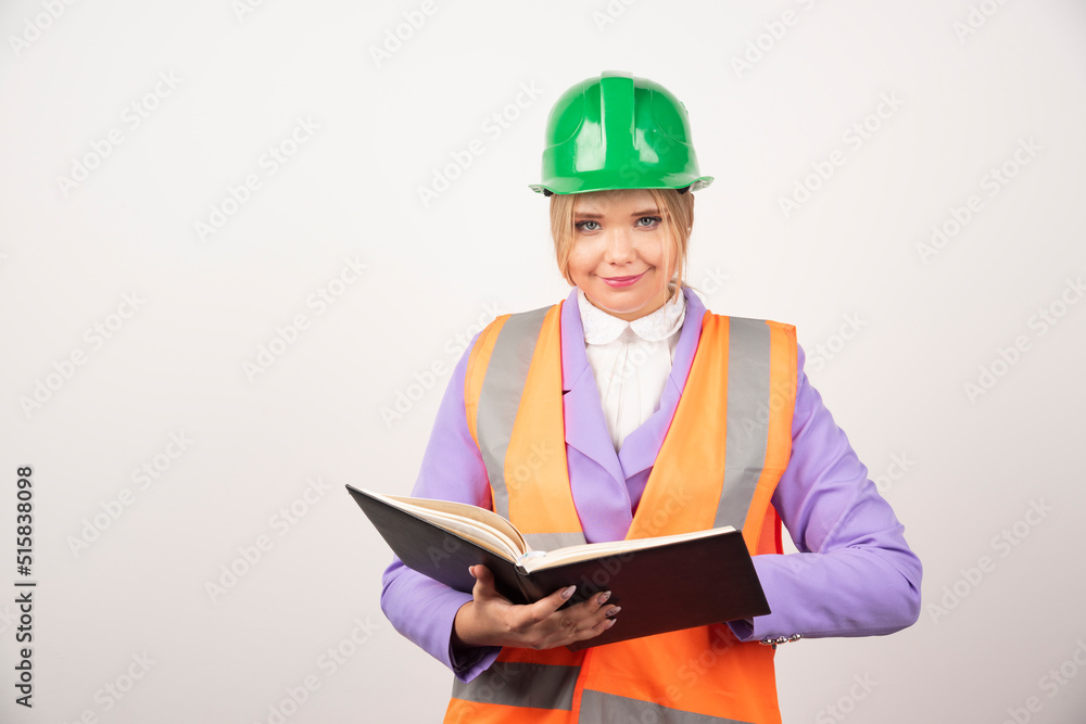 Young female builder in helmet holding tablet on white background Young female builder in helmet holding tablet on white background