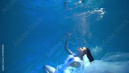 Slow Motion Girl on the ocean floor among the light beams passing through water.