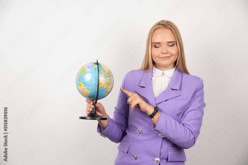 Fototapeta premium Female teacher pointing at globe on white background