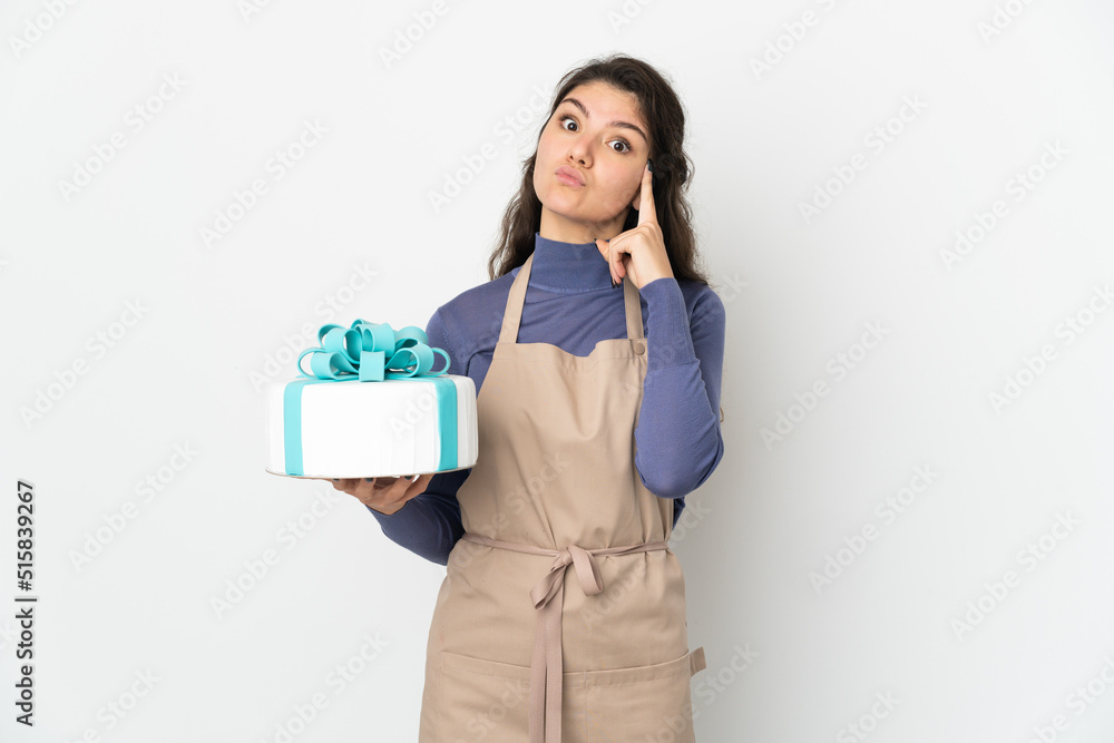 Pastry Russian chef holding a big cake isolated on white background thinking an idea Pastry Russian chef holding a big cake isolated on white background thinking an idea