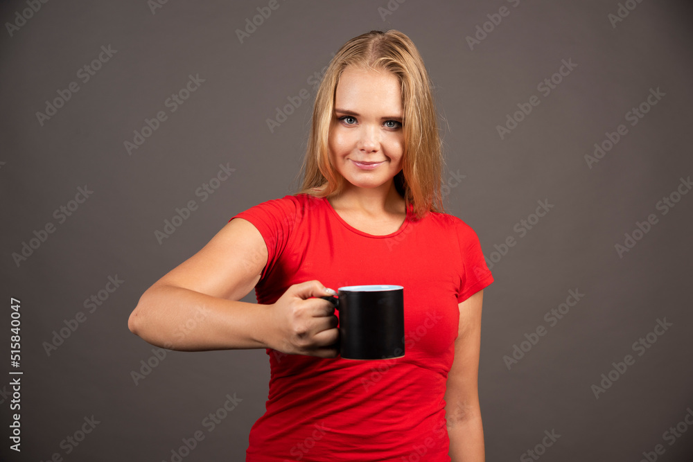 Young woman with empty cup standing on dark background Young woman with empty cup standing on dark background