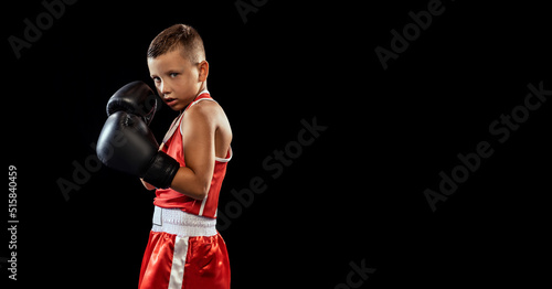 Young beginner boxer, sportive boy training isolated over dark background. Concept of sport, movement, studying, achievements, lifestyle. © master1305