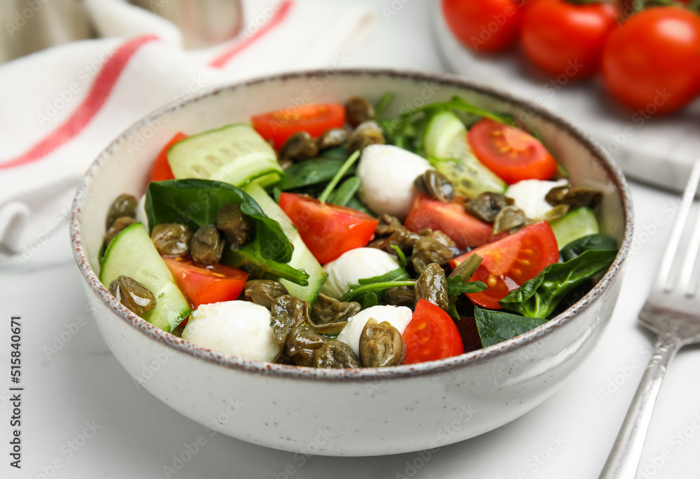 Salad with vegetables, capers and mozzarella in bowl on table, closeup