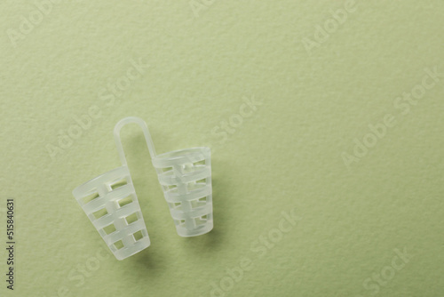 Nasal anti-snoring device on light green background, top view. Space for text