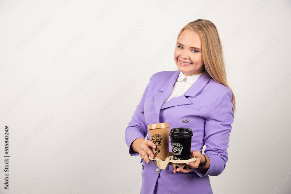 Smiling woman holding two cups of coffee on white background