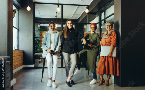 Multicultural female designers smiling at the camera in an office