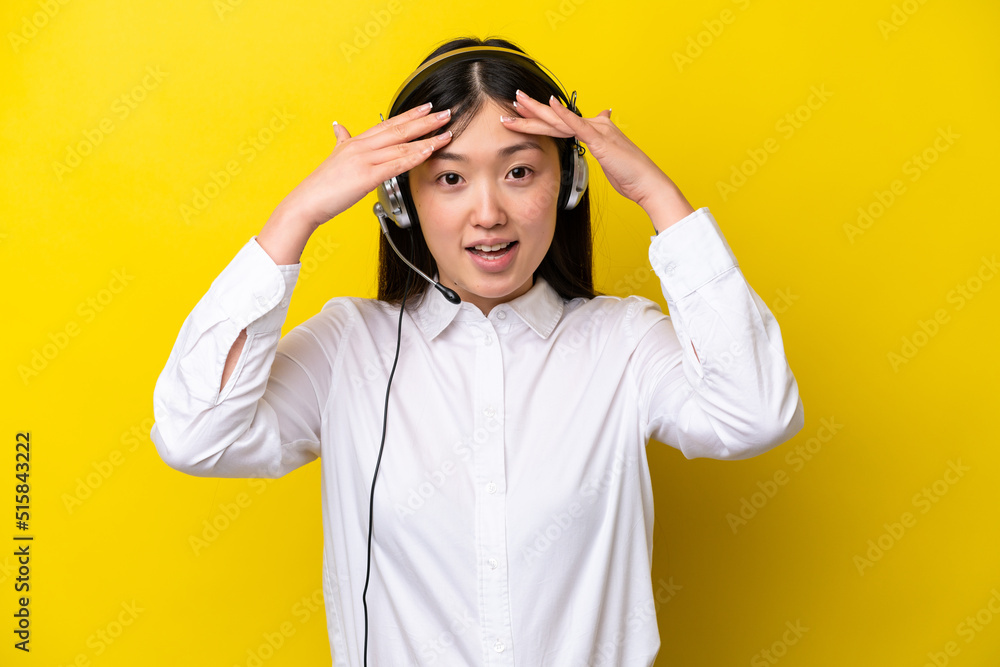 Telemarketer Chinese woman working with a headset isolated on yellow background with surprise expression Telemarketer Chinese woman working with a headset isolated on yellow background with surprise expression