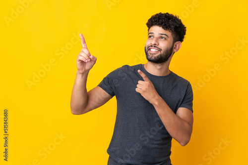 Young Moroccan man isolated on yellow background pointing with the index finger a great idea