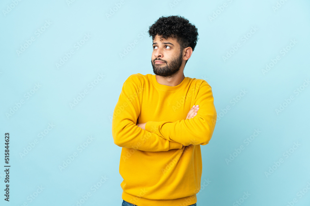 Young Moroccan man isolated on blue background making doubts gesture while lifting the shoulders Young Moroccan man isolated on blue background making doubts gesture while lifting the shoulders