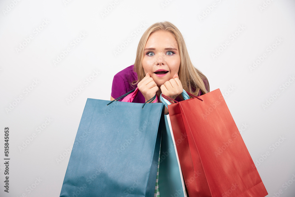 Blonde woman holding shopping bags with surprised expression