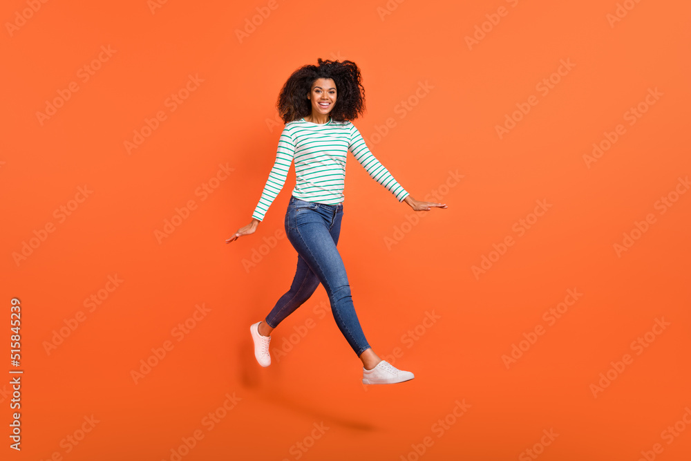 Full length photo of millennial lady run wear shirt jeans footwear isolated on orange background