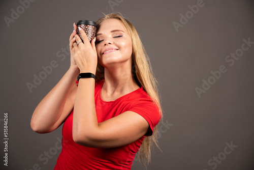 Blonde woman holding takeaway coffee with happy expression