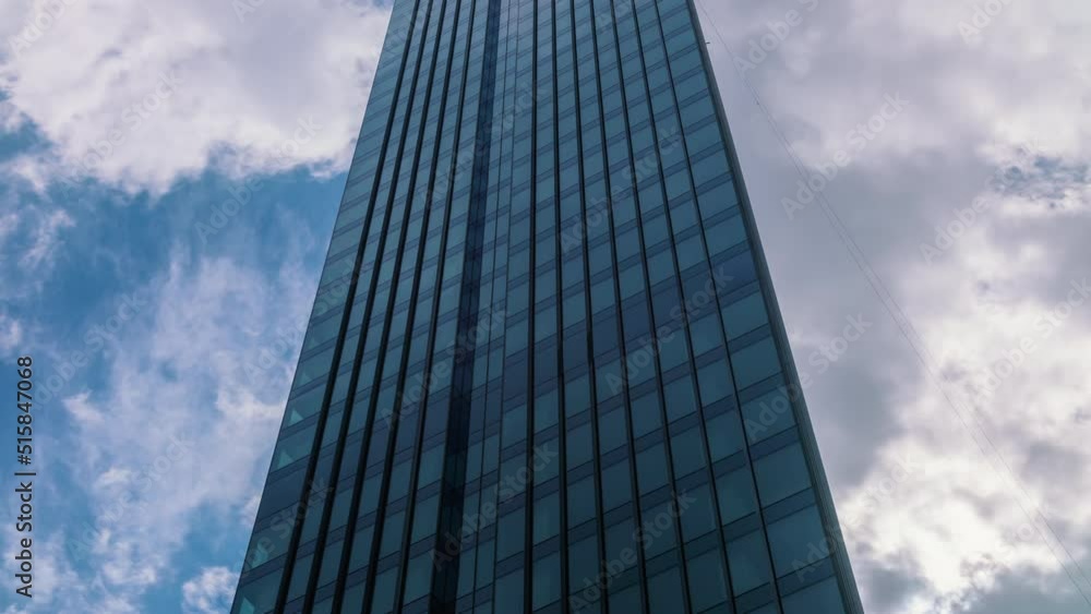 Timelapse modern skyscraper glass surface high office building, blue sky and clouds moving fast reflected on windows glass. Reflection time lapse downtown financial district on sunny day Timelapse modern skyscraper glass surface high office building, blue sky and clouds moving fast reflected on windows glass. Reflection time lapse downtown financial district on sunny day