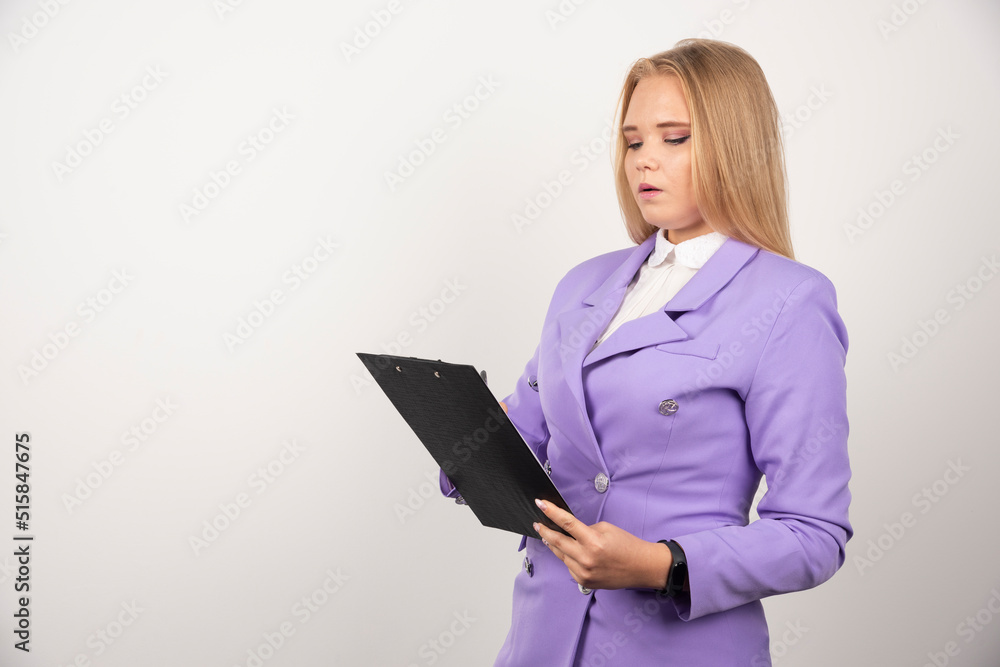 Portrait of young business woman standing and looking on clipboard Portrait of young business woman standing and looking on clipboard