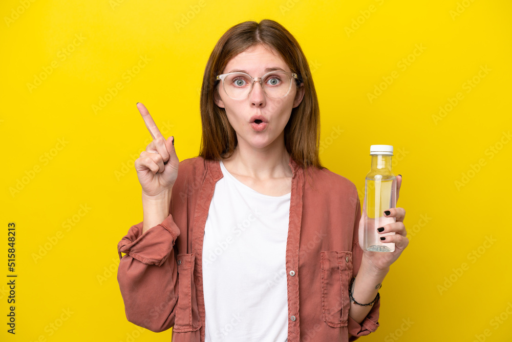 Young English woman with a bottle of water isolated on yellow background intending to realizes the solution while lifting a finger up Young English woman with a bottle of water isolated on yellow background intending to realizes the solution while lifting a finger up