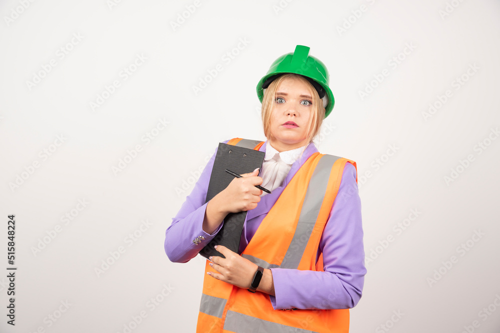 Young female contractor with green helmet and clipboard on white background Young female contractor with green helmet and clipboard on white background