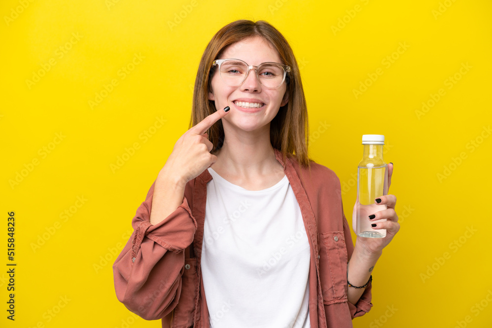 Young English woman with a bottle of water isolated on yellow background giving a thumbs up gesture Young English woman with a bottle of water isolated on yellow background giving a thumbs up gesture