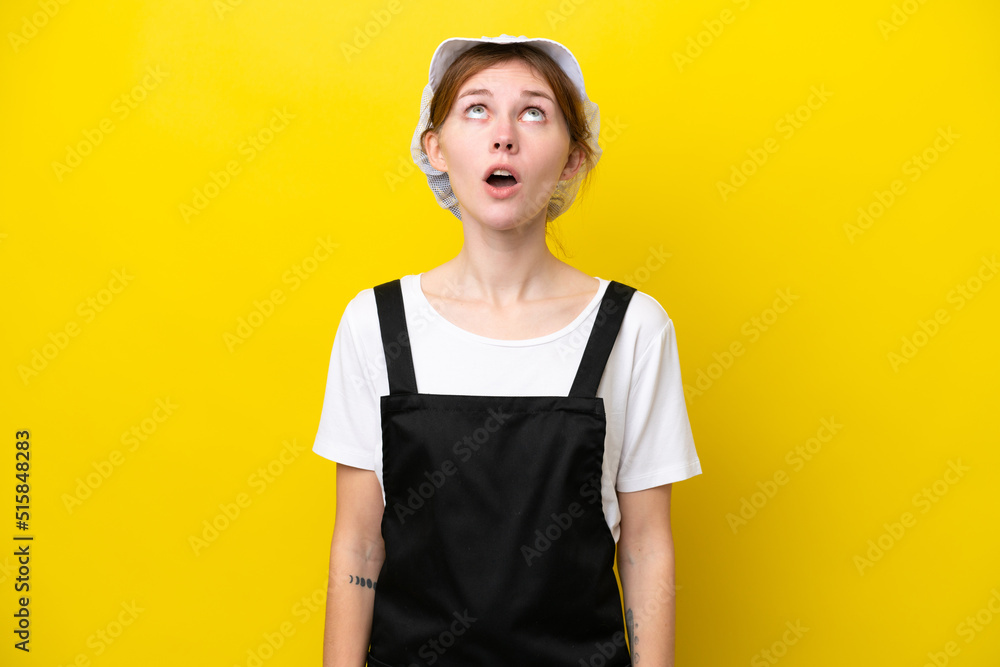 Young English fisherwoman isolated on yellow background looking up and with surprised expression Young English fisherwoman isolated on yellow background looking up and with surprised expression