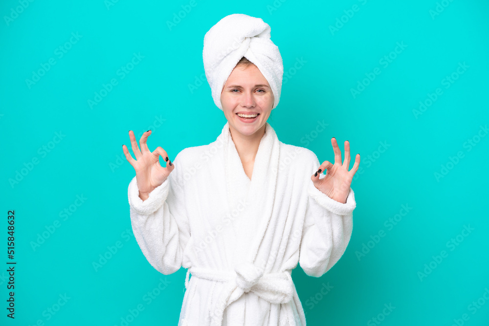 Young woman in a bathrobe isolated on blue background showing an ok sign with fingers Young woman in a bathrobe isolated on blue background showing an ok sign with fingers