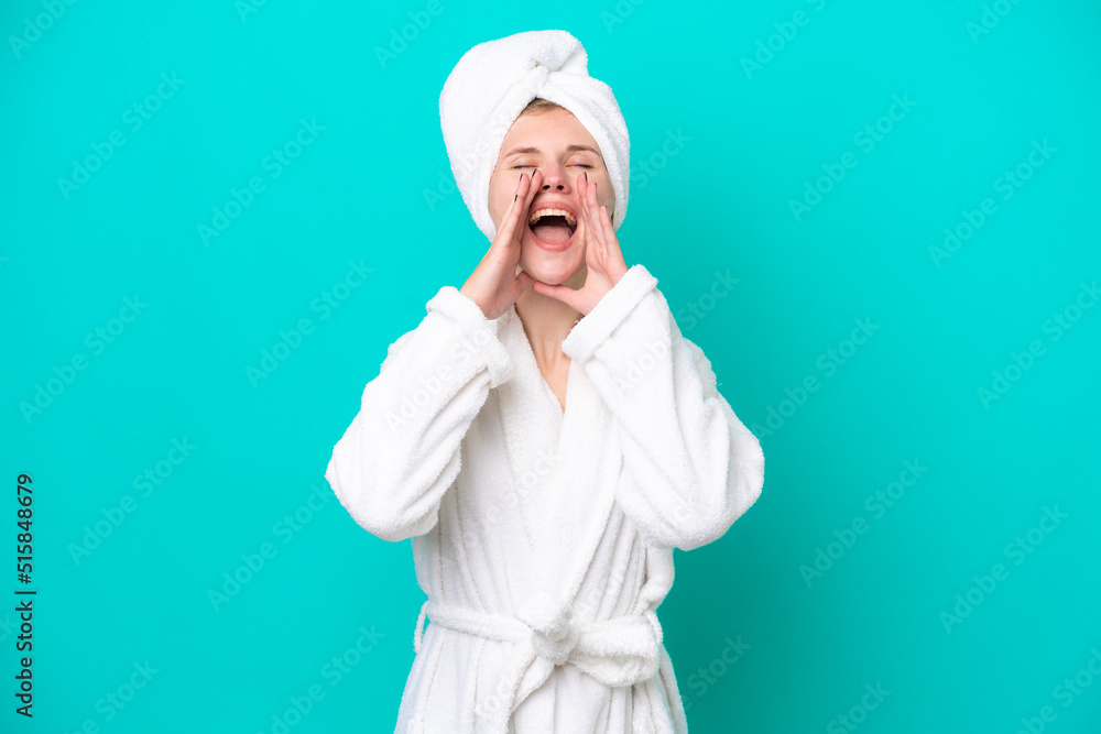 Young woman in a bathrobe isolated on blue background shouting and announcing something Young woman in a bathrobe isolated on blue background shouting and announcing something