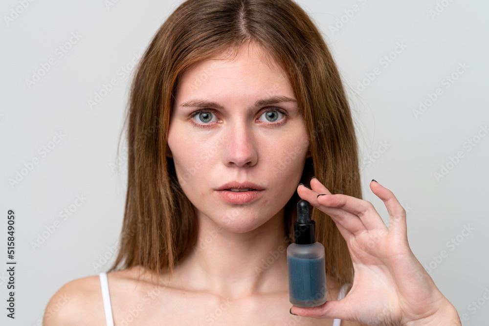 Young English woman holding a serum. Close up portrait Young English woman holding a serum. Close up portrait